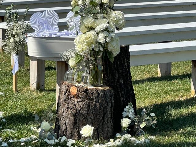 White flower arrangement set on a tree stump beside a white railing outdoors