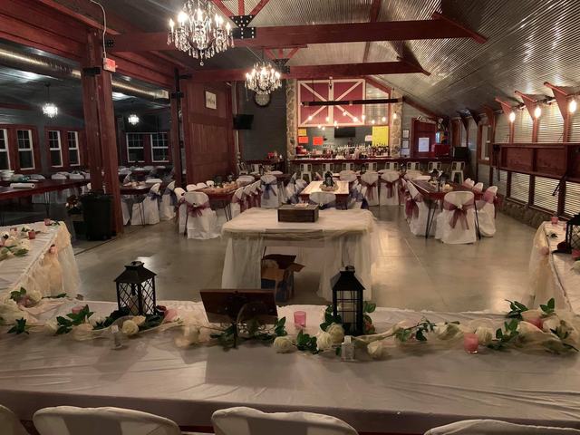 Red barn event hall with a round table set with lanterns, florals and chandeliers overhead