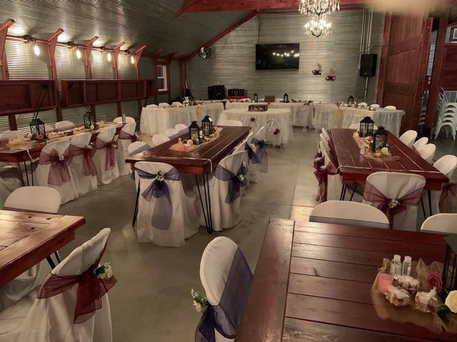 Tables with white linens and pink-sashed chair covers in a rustic hall with a wood floor