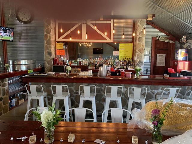 Bar area with white stools, flower arrangements on the counter, and a stone wall with barn-door decor