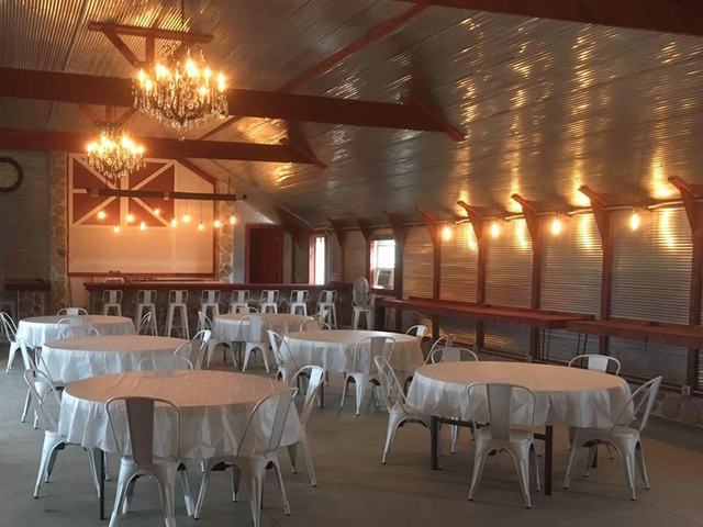 Banquet hall with round tables covered in white linens, white chairs, and warm lighting
