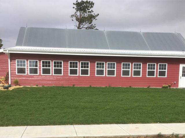 Red barn event building with white-trimmed windows and a green lawn out front